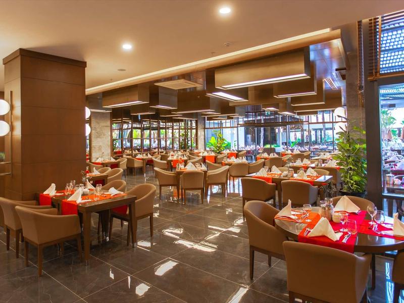 Restaurant moderne avec tables élégantes, chaises et éclairage chaleureux.