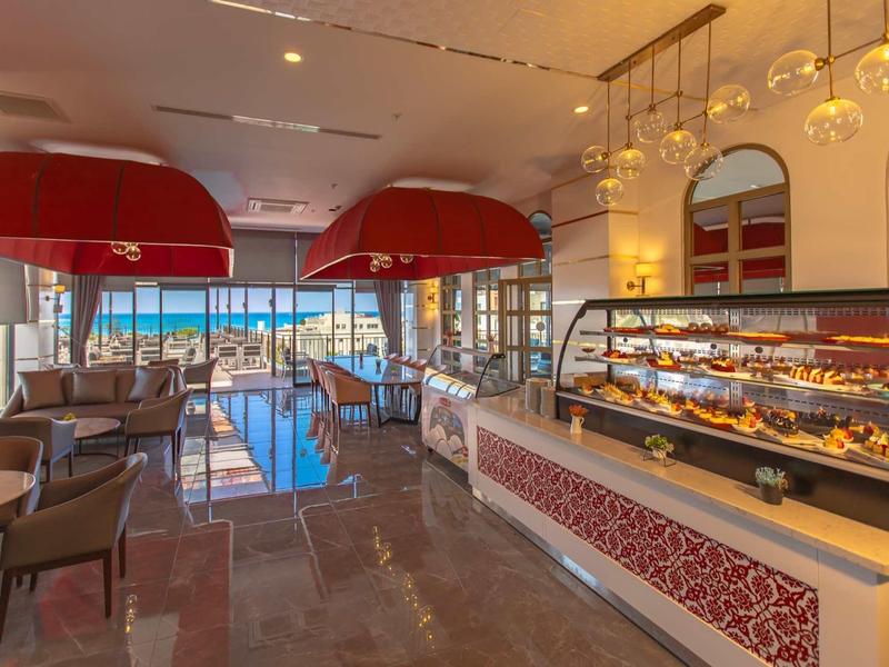 Café moderne avec sièges et vitrine à pâtisseries avec vue sur la mer.