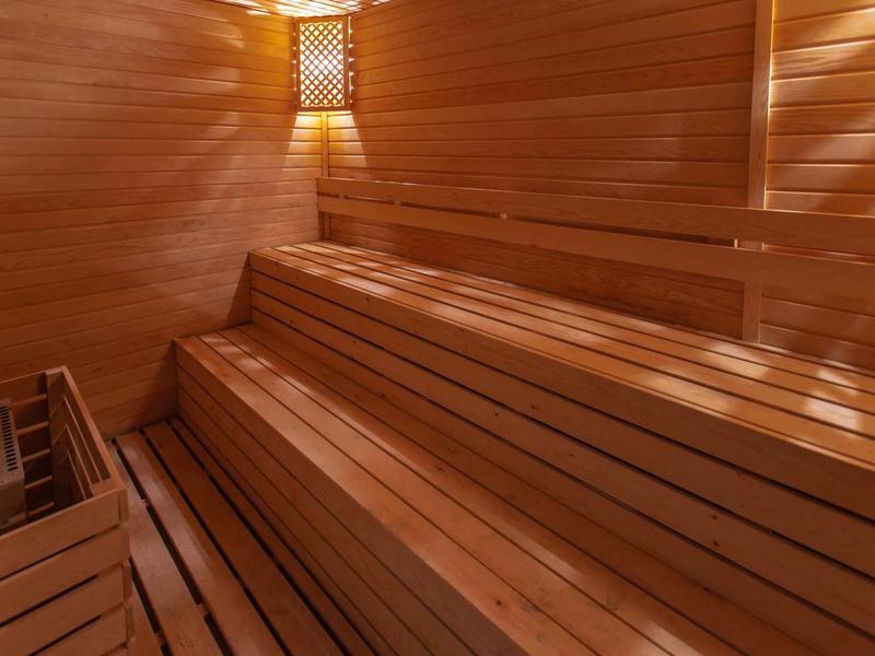 Intérieur d'un sauna en bois avec des bancs à trois niveaux et un éclairage chaleureux.