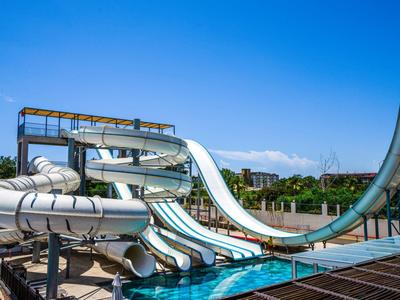 Moderní vodní skluzavky v aquaparku pod jasně modrou oblohou.