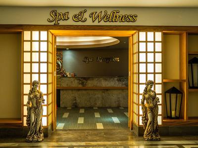 Vstup do spa a wellness s dřevěnými sochami a lampami.