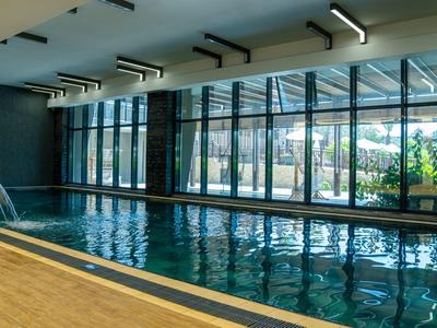 Vnitřní bazén s velkými okny směřujícími do světlé zahrady.