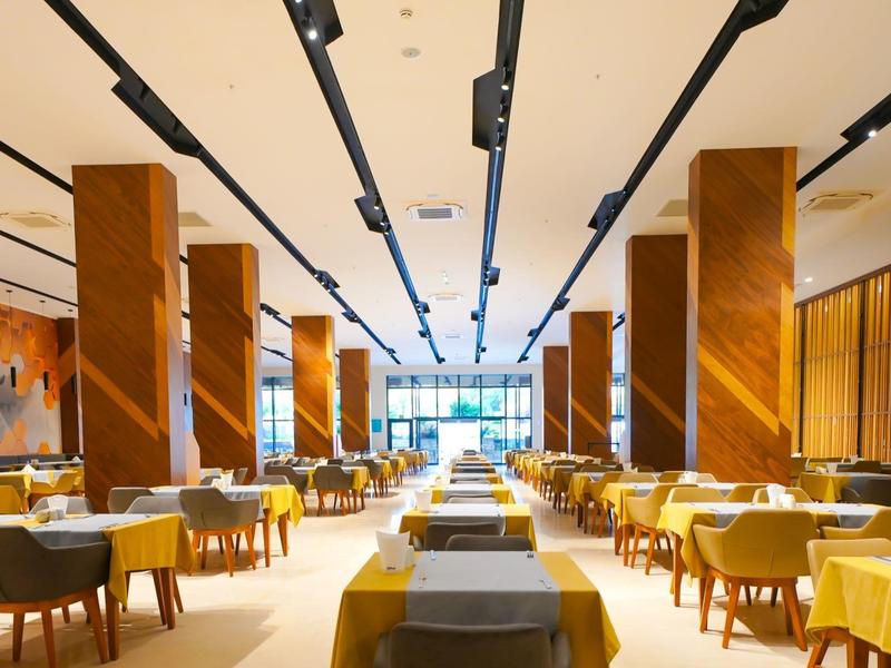 Velká elegantní restaurace s dřevěnými stoly, židlemi a množstvím přirozeného světla.