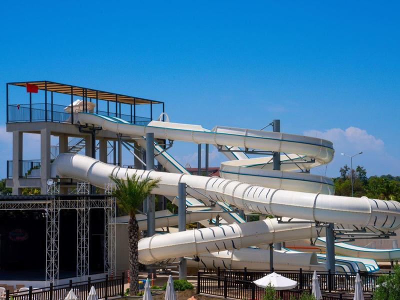 Velká bílá vodní skluzavka v aquaparku venku pod modrou oblohou.