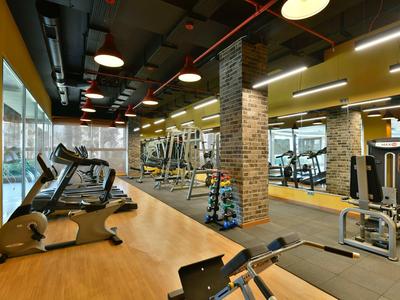 Moderne Fitnessstudio mit Laufbändern, Hanteln, Spiegeln und hellen gelben Wänden.