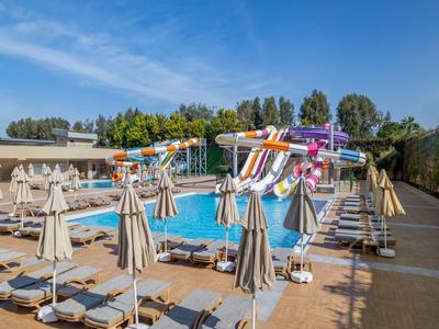 Gran piscina con toboganes y muchas tumbonas en un día soleado.