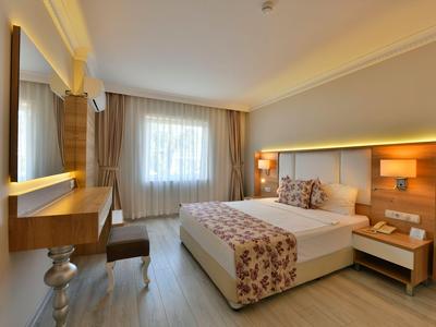 Habitación de hotel moderna con cama doble, escritorio y ventana con cortinas claras.