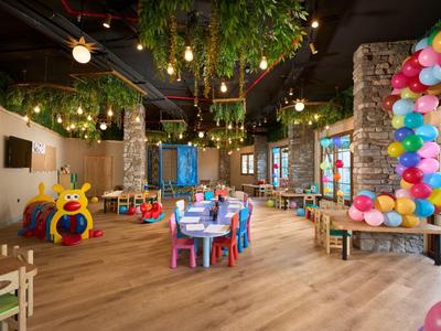 Interior colorido y amigable para niños con mesas, juguetes y globos en una habitación luminosa y espaciosa.