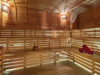 Eine große Sauna mit hölzernen Bänken, Wänden und Beleuchtung für Entspannung.