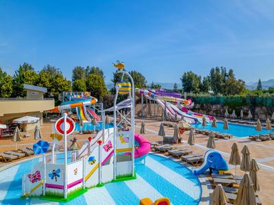 Colorido parque acuático de hotel con toboganes, piscinas y tumbonas bajo cielo despejado.