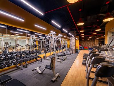 Gimnasio moderno de hotel con pesas, máquinas y cintas de correr.