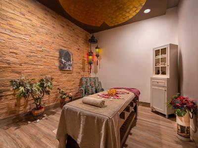 Una habitación de masajes acogedora con suelo de madera, pared de piedra y decoración relajante.
