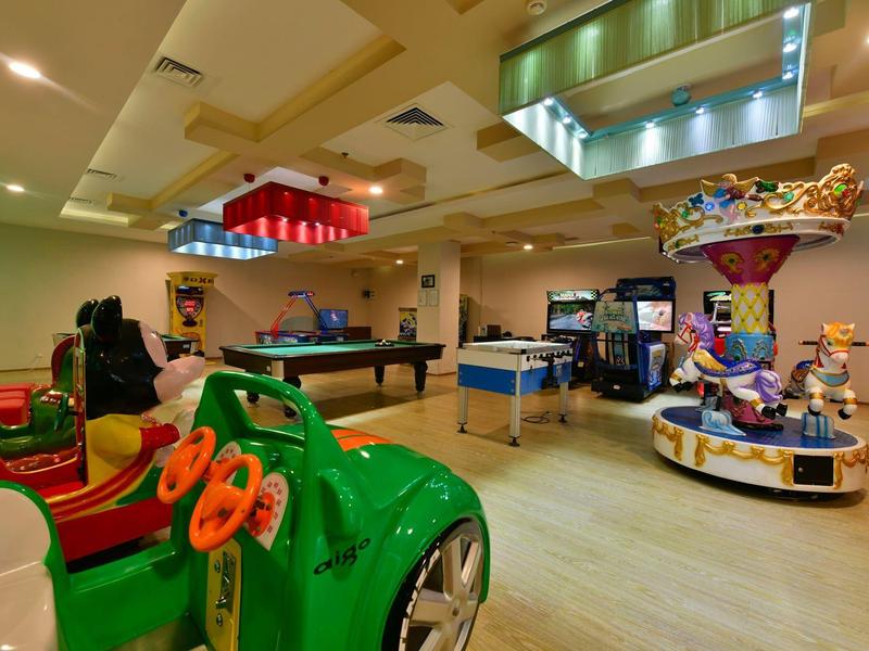 Binnenruimte met speeltoestellen en tafels in een kindvriendelijke hotel speelkamer.