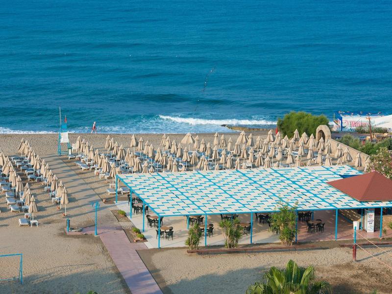 Leeg strand met rijen opgevouwen parasols en overdekt gebied bij de zee
