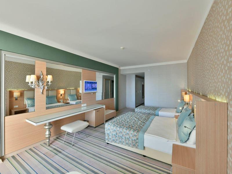 Modern ingerichte hotelkamer met tweepersoonsbed, zithoek en grote spiegelwand.