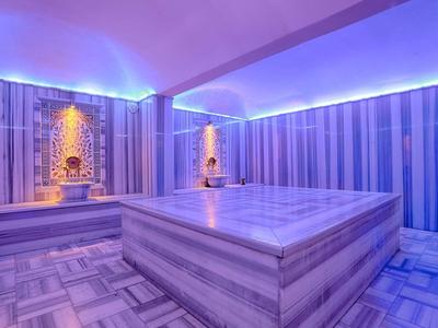 Moderner Hamam mit Marmorwänden, zentralem beheiztem Stein und blauer LED-Beleuchtung.