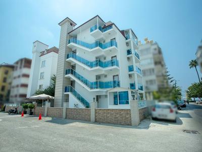 Sechsstöckiges weißes Gebäude mit blauen Treppen, umgeben von Straßen und Autos.