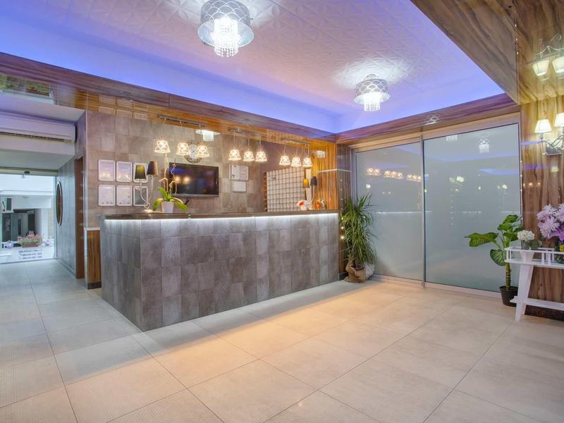 Moderner Empfangsbereich mit grauer Theke, Holzdecke, Deckenleuchten und blauer LED-Beleuchtung.