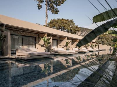 Moderní hotelový bazén s lehátky a rostlinami v klidném prostředí.