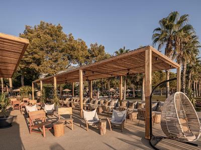 Prostorná venkovní plocha s dřevěnými pergolami a posezením v hotelu nebo resortu.