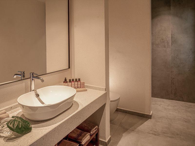 Moderní koupelna s umyvadlem na pracovní desce a jednoduchým interiérem.