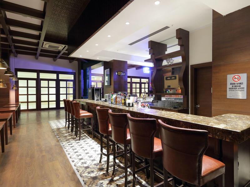 Moderne bar met hoge stoelen, marmeren blad, houten vloer en warme verlichting in een hotel.