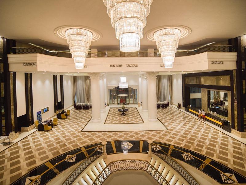 Luxe hotel lobby met grote kroonluchters, patroon tapijt en elegante zitgedeeltes.