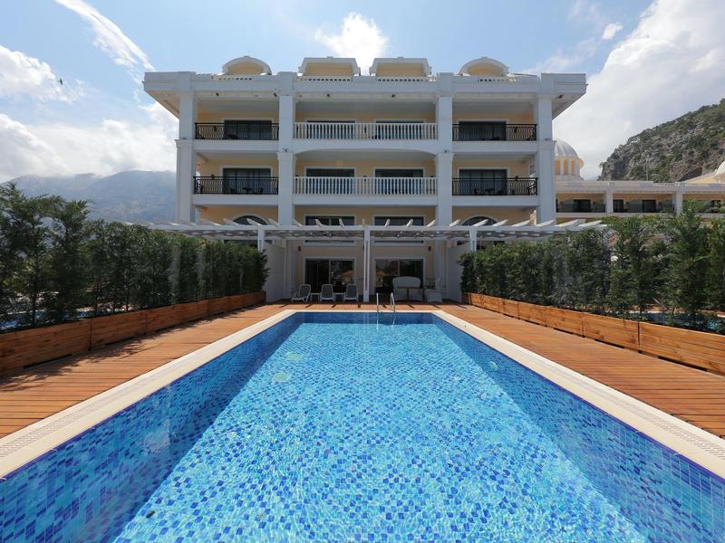 Modern hotel met een lang buitenzwembad omgeven door houten terrassen en groen.