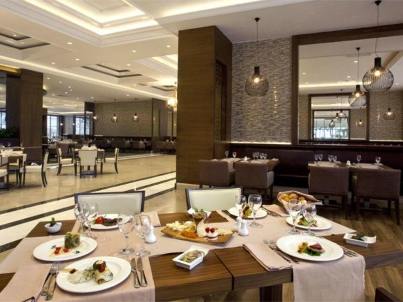 Ruim hotelrestaurant met elegante tafels, gestoffeerde stoelen en mooi opgemaakte gerechten.