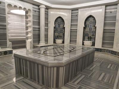 Elegante hamam met grijze marmeren muren, zuilen en centrale wasruimte.