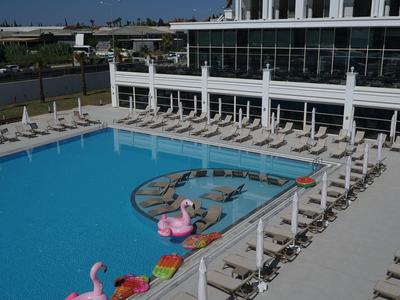 Modern hotelzwembad met ligstoelen en parasols omgeven door hotelgebouwen.