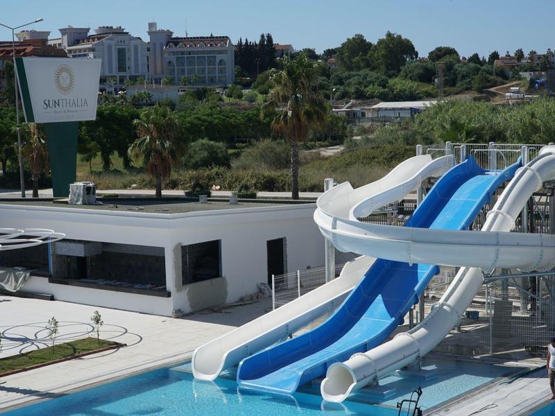 Waterpark met meerdere blauwe glijbanen en een zwembad voor gebouwen en bomen.