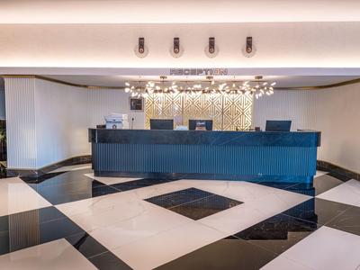 Recepción de hotel moderna con mostrador negro y suelo de baldosas en blanco y negro.