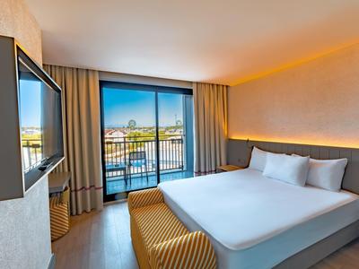 Habitación de hotel moderna con cama grande, ventana panorámica y vista a la ciudad.