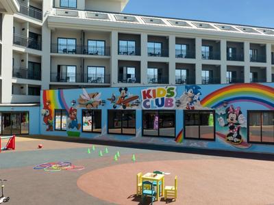 Hotel de varios pisos con zona de juegos infantil colorida y espacio al aire libre.