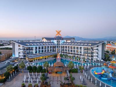 Hotel resort moderno con piscinas, tumbonas y parque acuático al atardecer