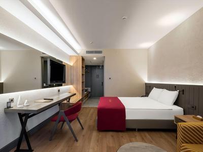 Camera d'hotel moderna con letto matrimoniale, scrivania e TV a schermo piatto.
