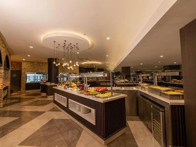 Área de buffet moderna con islas iluminadas y variedad de platillos en un restaurante de hotel.