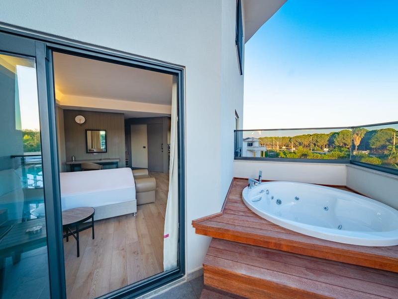 Balcón con jacuzzi y dormitorio abierto en una habitación de hotel moderna con hermosa vista.