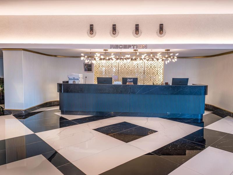 Recepción de hotel moderna con mostrador negro y suelo de baldosas en blanco y negro.