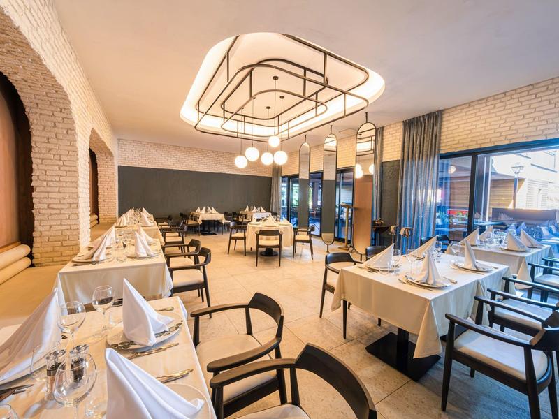 Restaurante elegante con mesas bien organizadas, sillas negras y gran lámpara colgante moderna.