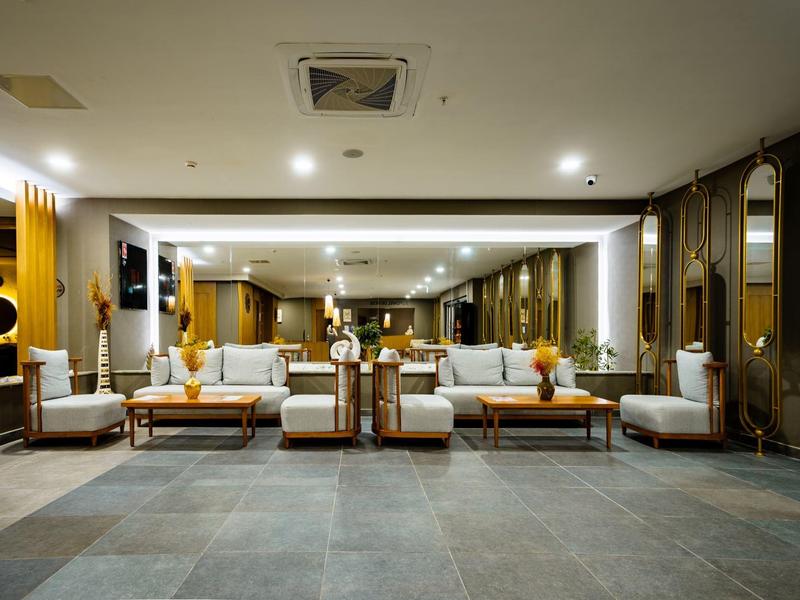 Amplia sala de estar del hotel con iluminación moderna, grupos de asientos cómodos y decoración elegante.