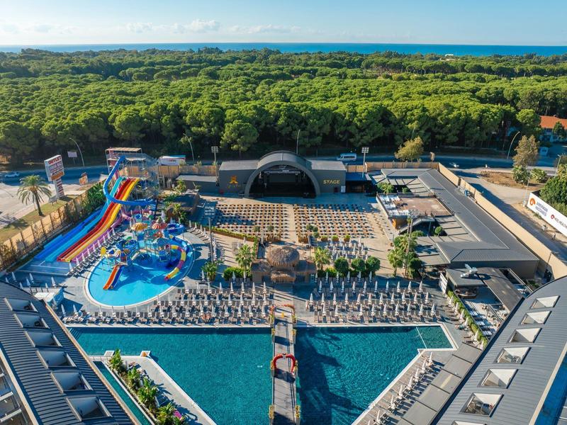 Gran parque acuático con muchos toboganes, piscina y tumbonas junto al bosque y el mar.
