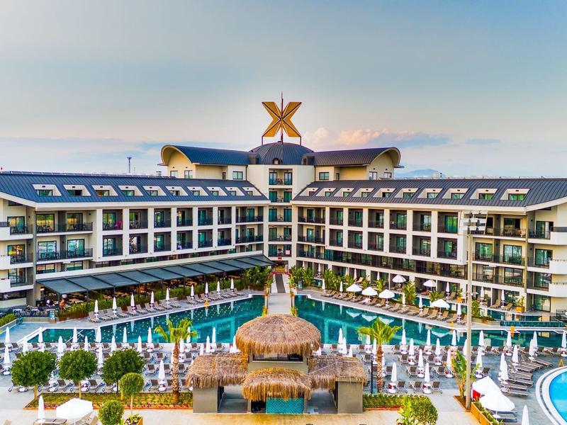 Complejo hotelero moderno con gran piscina al aire libre, palmeras y ambiente relajante al amanecer.