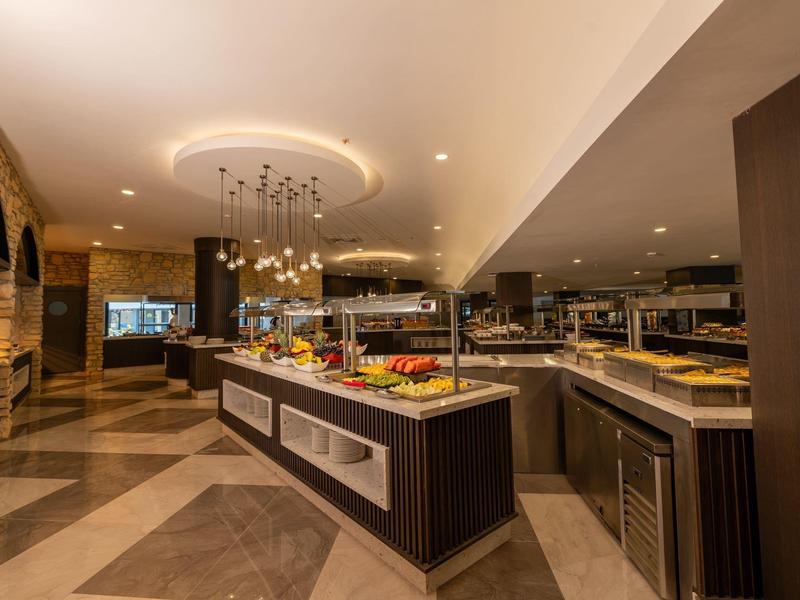 Área de buffet moderna con islas iluminadas y variedad de platillos en un restaurante de hotel.