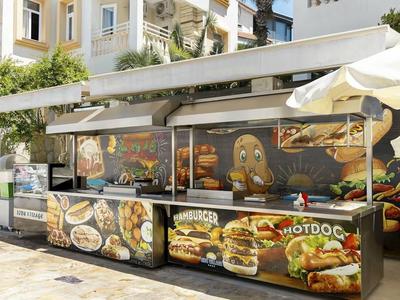 Ein Stand mit verschiedenen Bildern von Burgern, Hot Dogs und anderen Speisen vor einem hellen Gebäude.