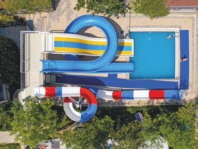 Moderner Gebäudekomplex mit großem blauen Pool und Palmen in einem Hotelresort.