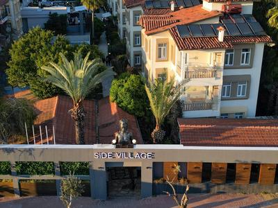 Moderner Hotelkomplex mit rotdachgedeckten Gebäuden und Palmen an sonnigem Tag.