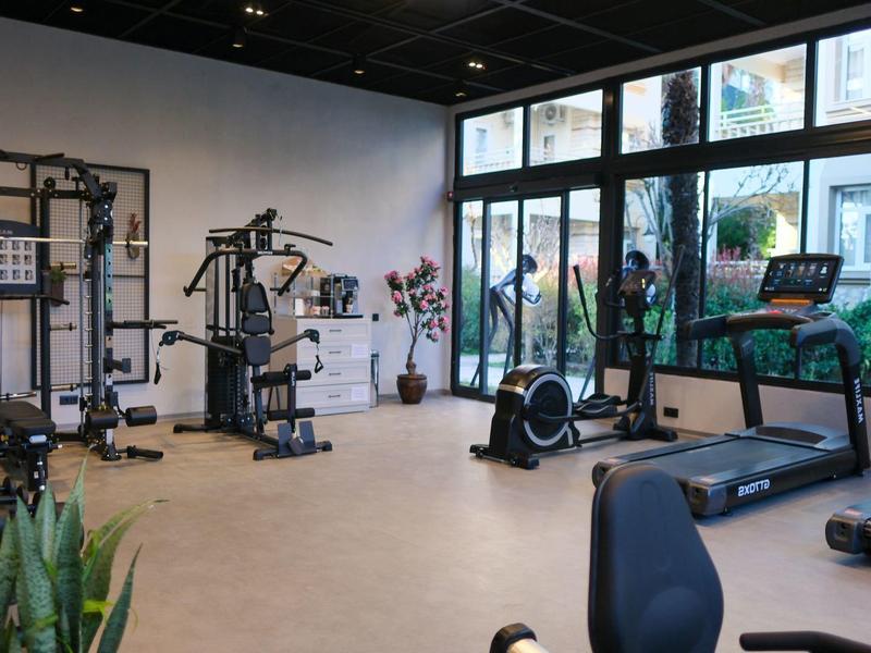 Moderner Fitnessraum mit Trainingsgeräten und Blick auf Terrasse und Garten