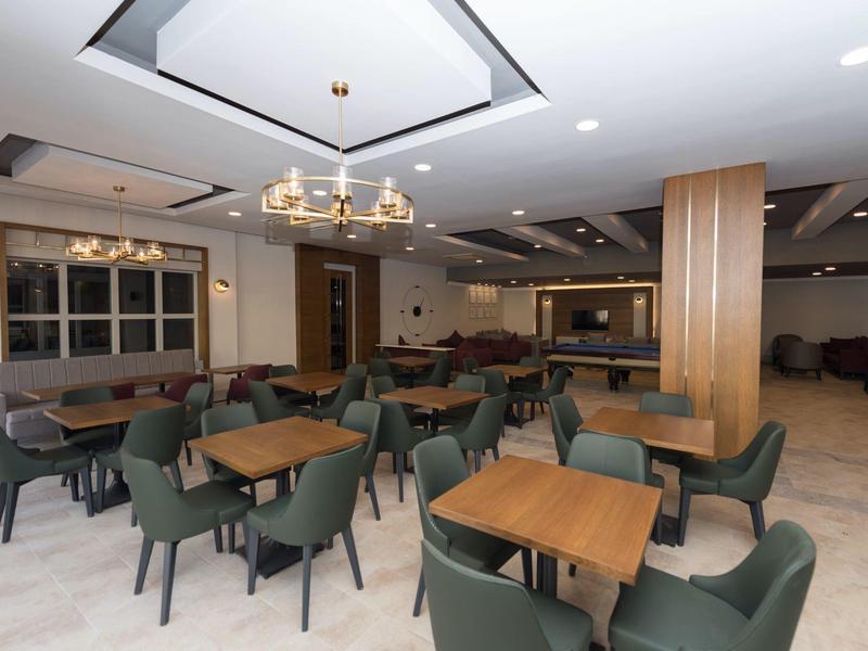 Moderner, leerer Frühstücksraum mit grünen Sitzstühlen und Holztischen in einem Hotel